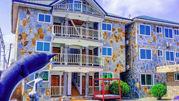 Un edificio de varios pisos con fachada de piedra, una piscina y una estatua.