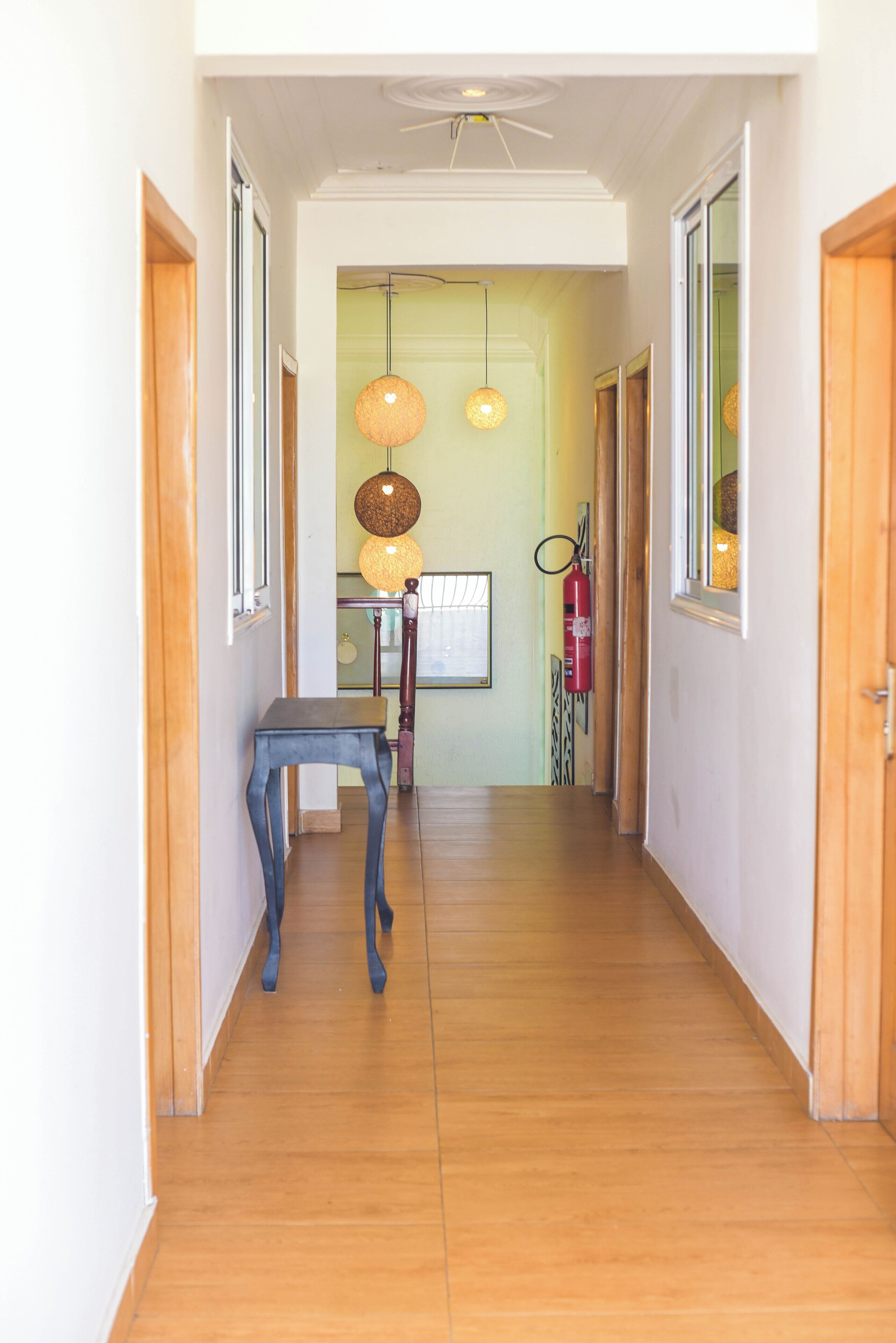 A hallway with wooden flooring, a table, and hanging lamps.