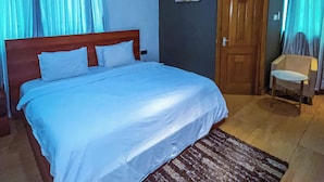 Una cama bien hecha con sábanas blancas, un cabecero de madera y un tapete marrón estampado.