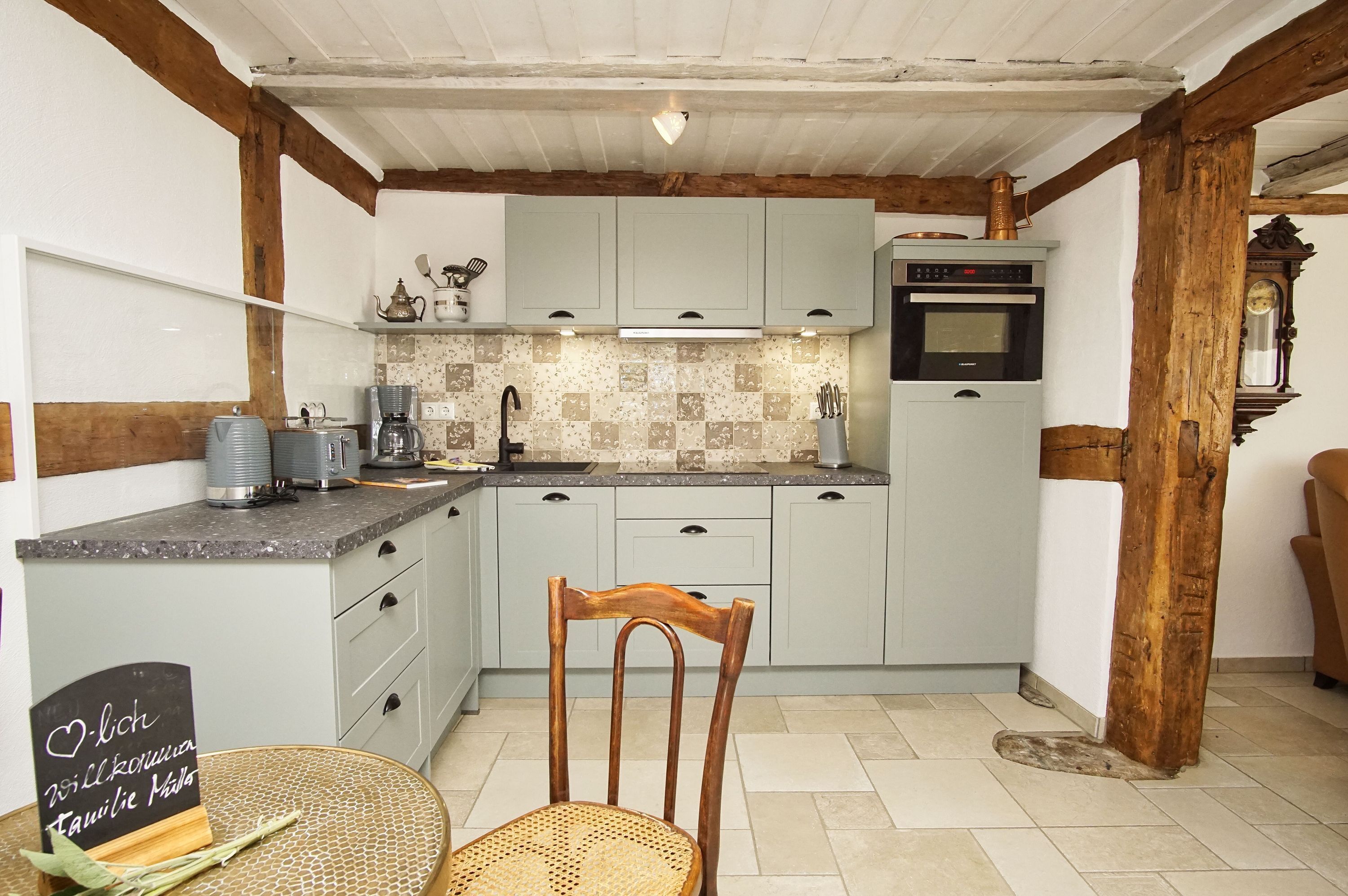 A kitchen with light blue cabinets, a wooden chair, and a sign on the table.