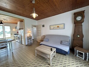 Un salon chaleureux avec un canapé, une table basse en bois, une horloge et un sol carrelé.