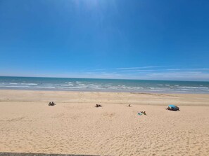 Une plage avec un ciel dégagé et une mer calme.