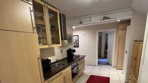 Una cocina compacta con armarios de madera, un lavamanos de acero inoxidable y una alfombra roja.