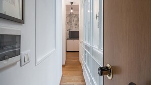 A hallway with a wooden door, a light switch, and a framed picture on the wall.