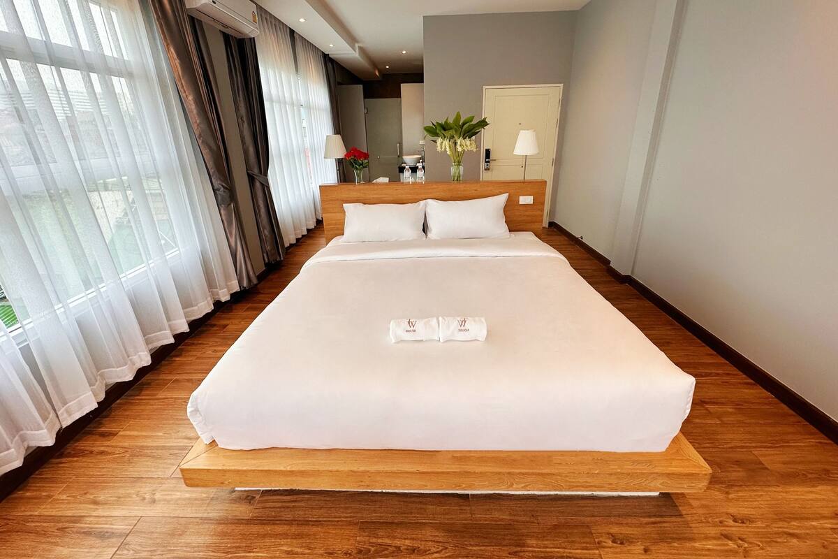 A large, neatly made bed with a wooden headboard in a hotel room.