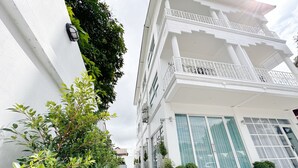 A multi-story building with balconies, a pathway with stepping stones, and potted plants along the walkway. - The White House Rachamankha (Chiang Mai)