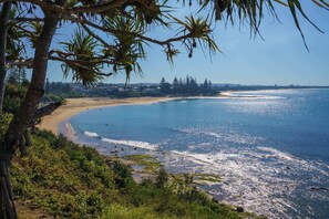 A coastal landscape with a beach, clear blue sea, and greenery.