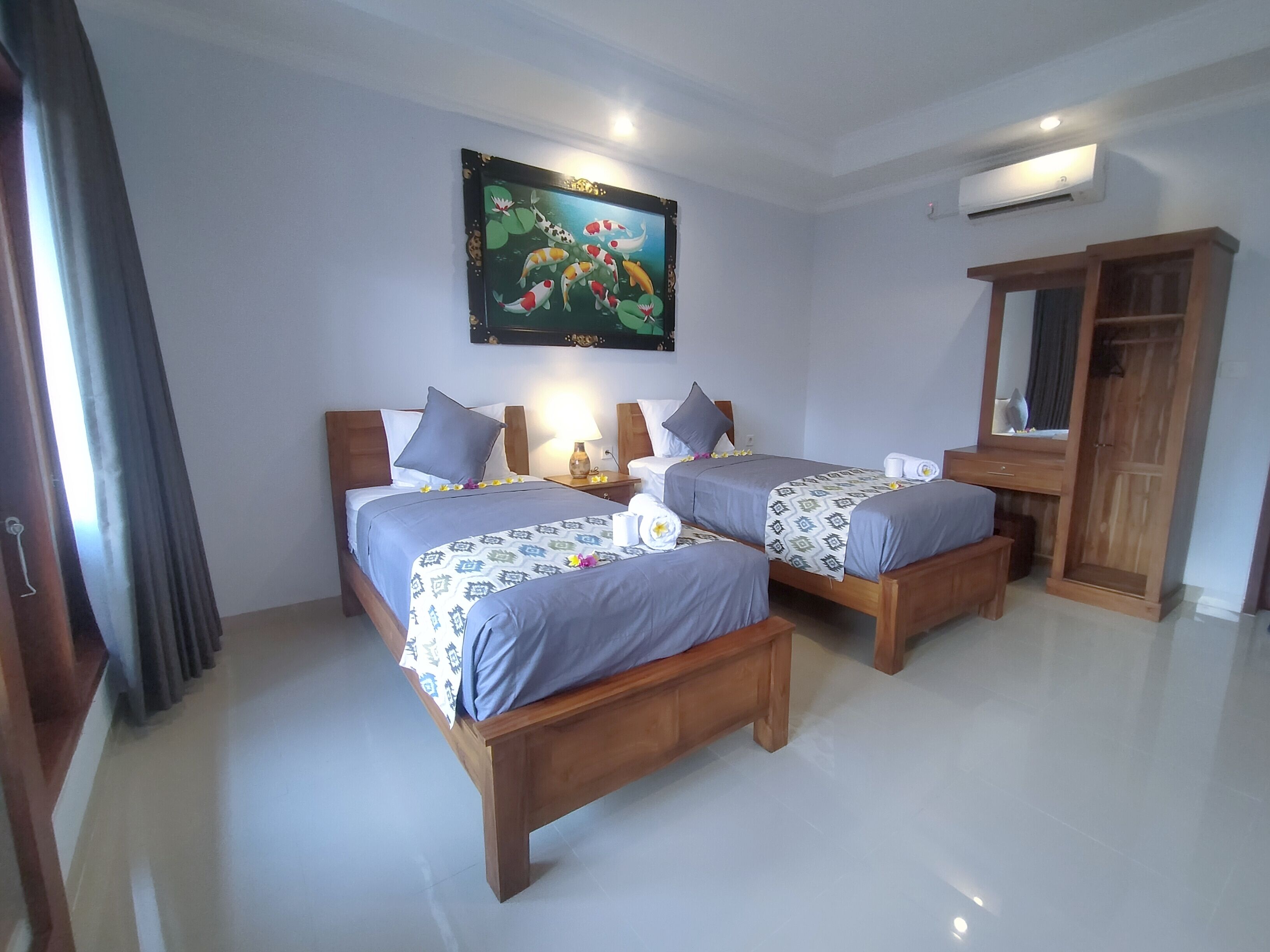 A hotel room with two wooden beds, a large mirror, and a painting of fish on the wall.