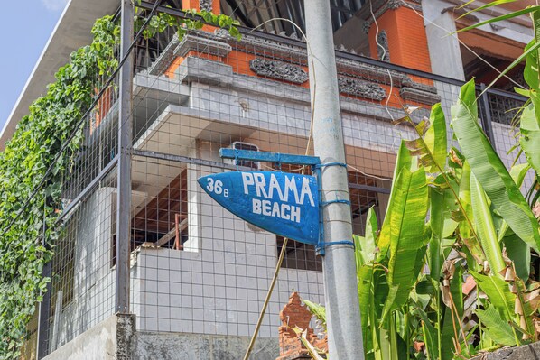 A sign for "Prama Beach" with a blue background and white lettering, attached to a metal pole.