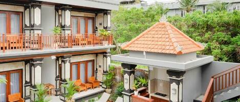 A two-story building with a balcony, outdoor seating, and a pool.