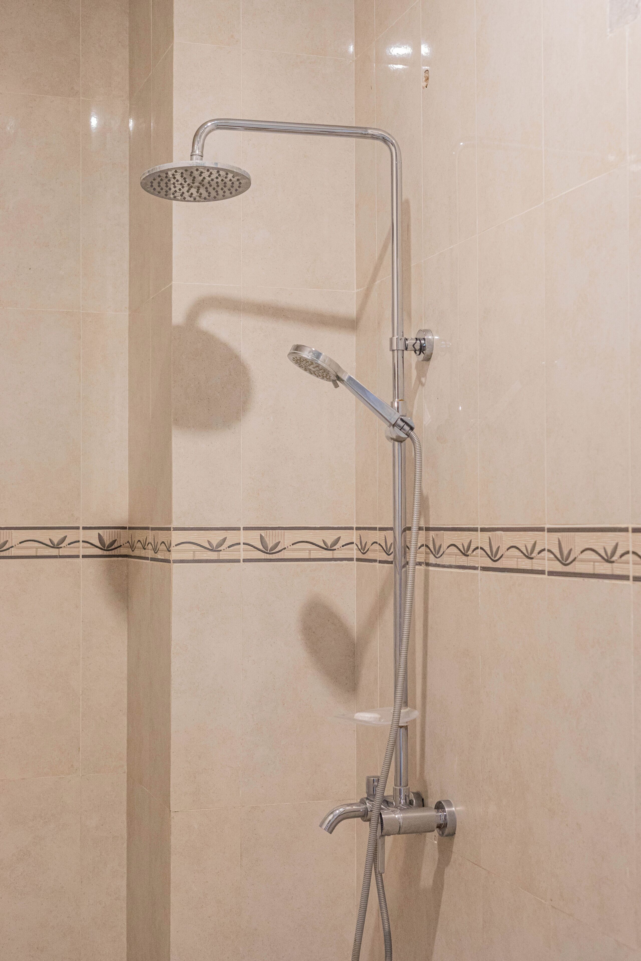 A shower with a handheld showerhead and a wall-mounted faucet.