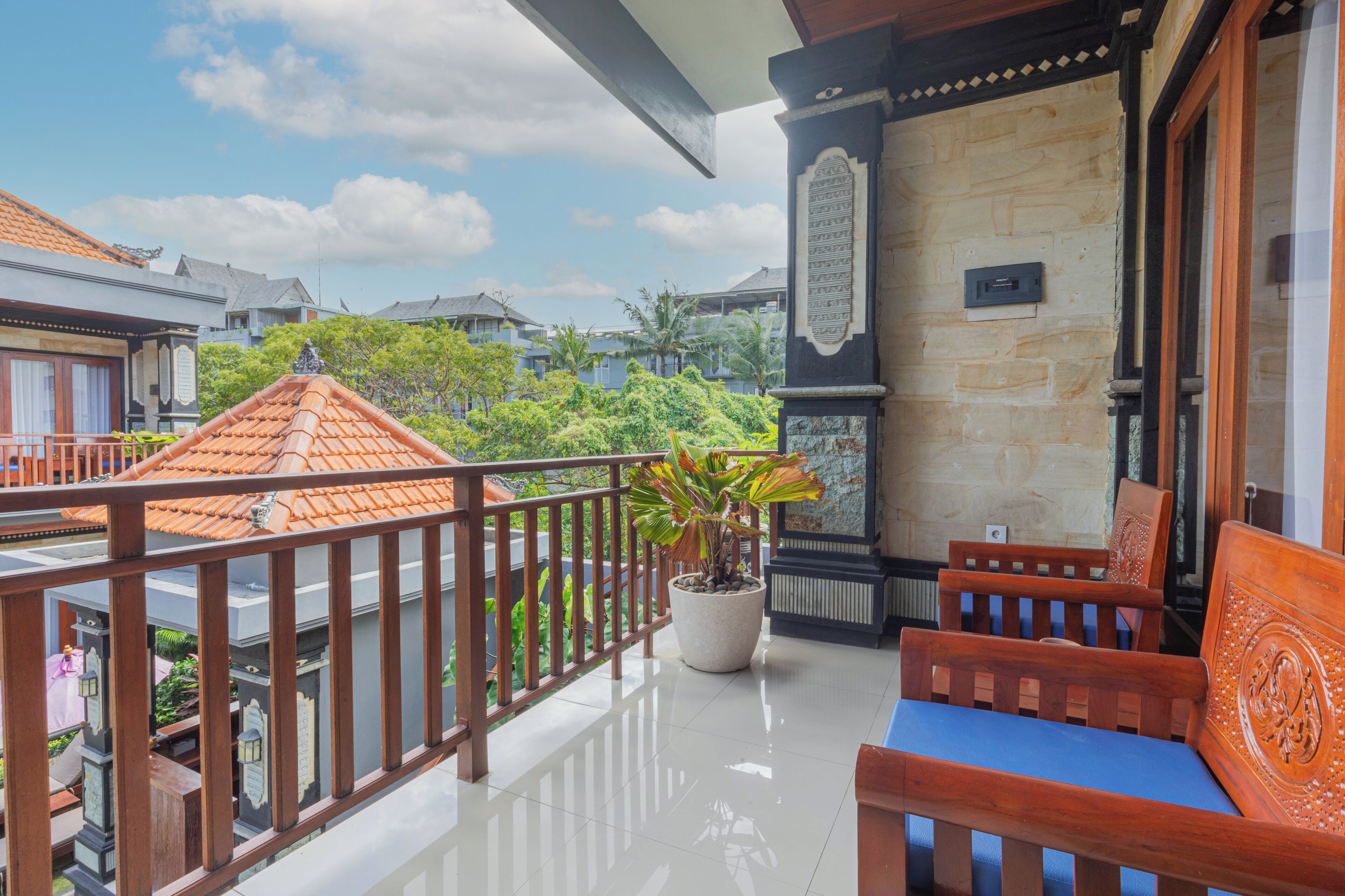 A balcony with a potted plant, wooden furniture, and a stone wall with a plaque.