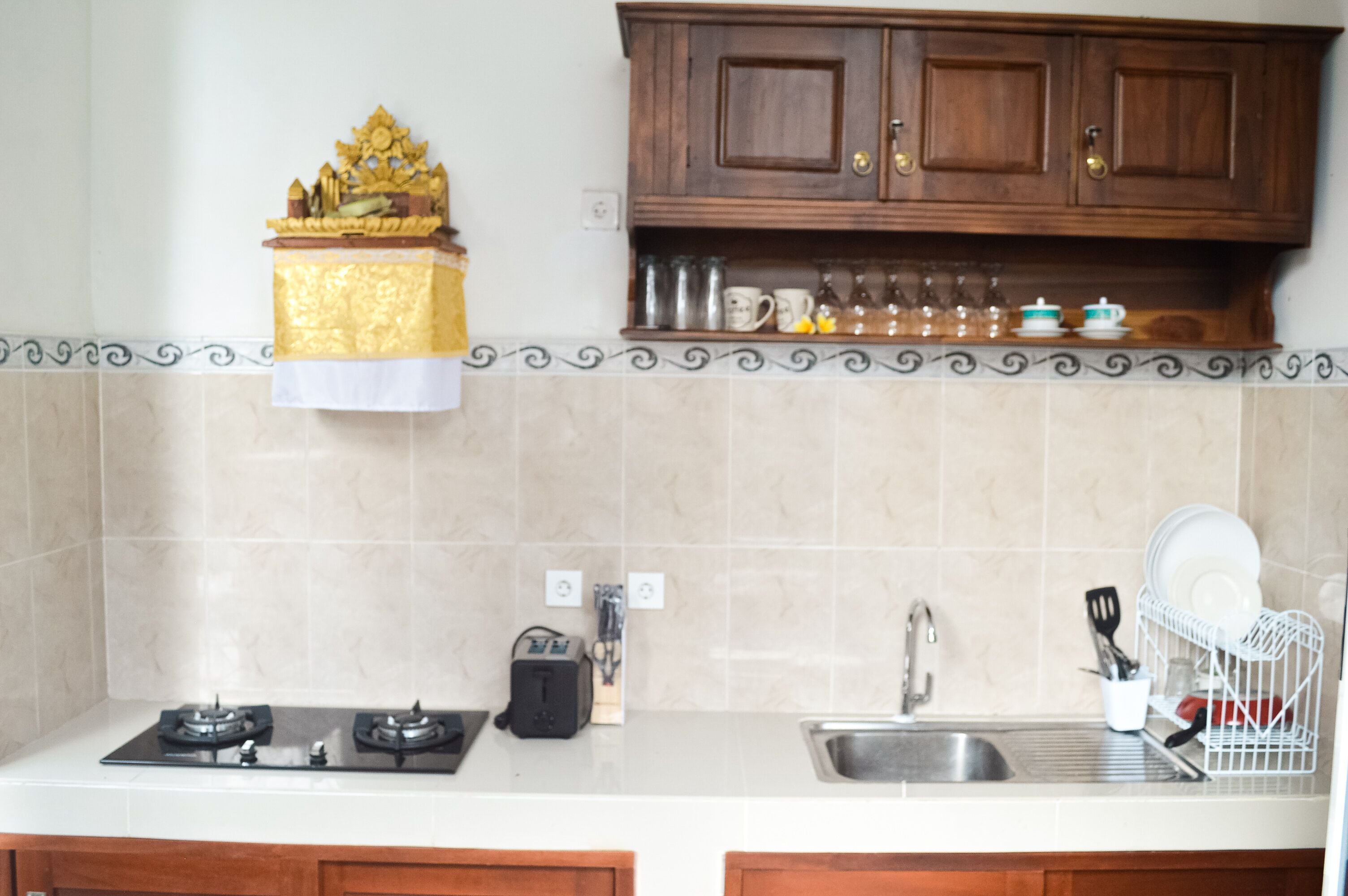 A kitchen with a gas stove, a toaster, a sink, and a dish rack.
