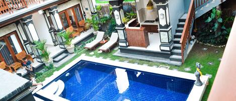 A residential building with a swimming pool, outdoor seating, and a staircase.