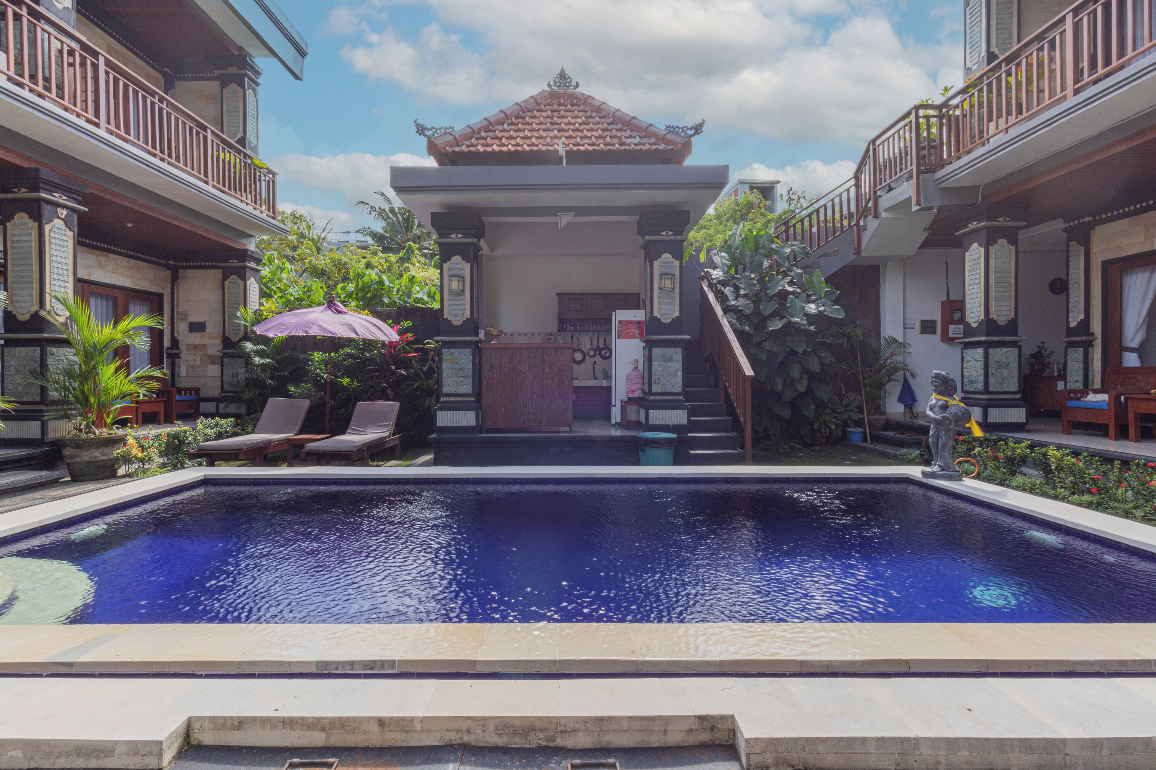 A swimming pool with a traditional Balinese architectural structure in the background.