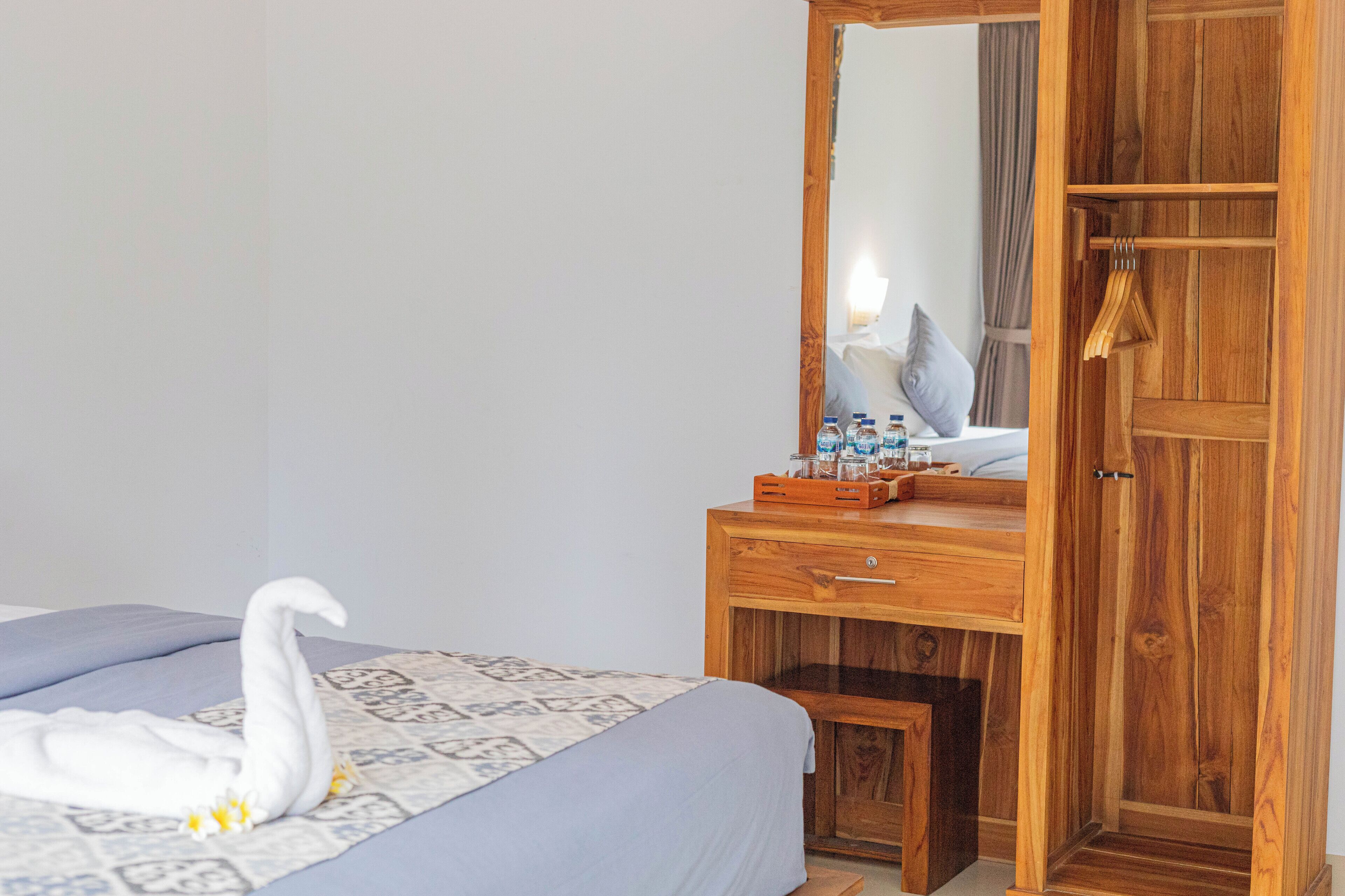A bedroom with a bed, a wooden dresser, a mirror, and a wardrobe.