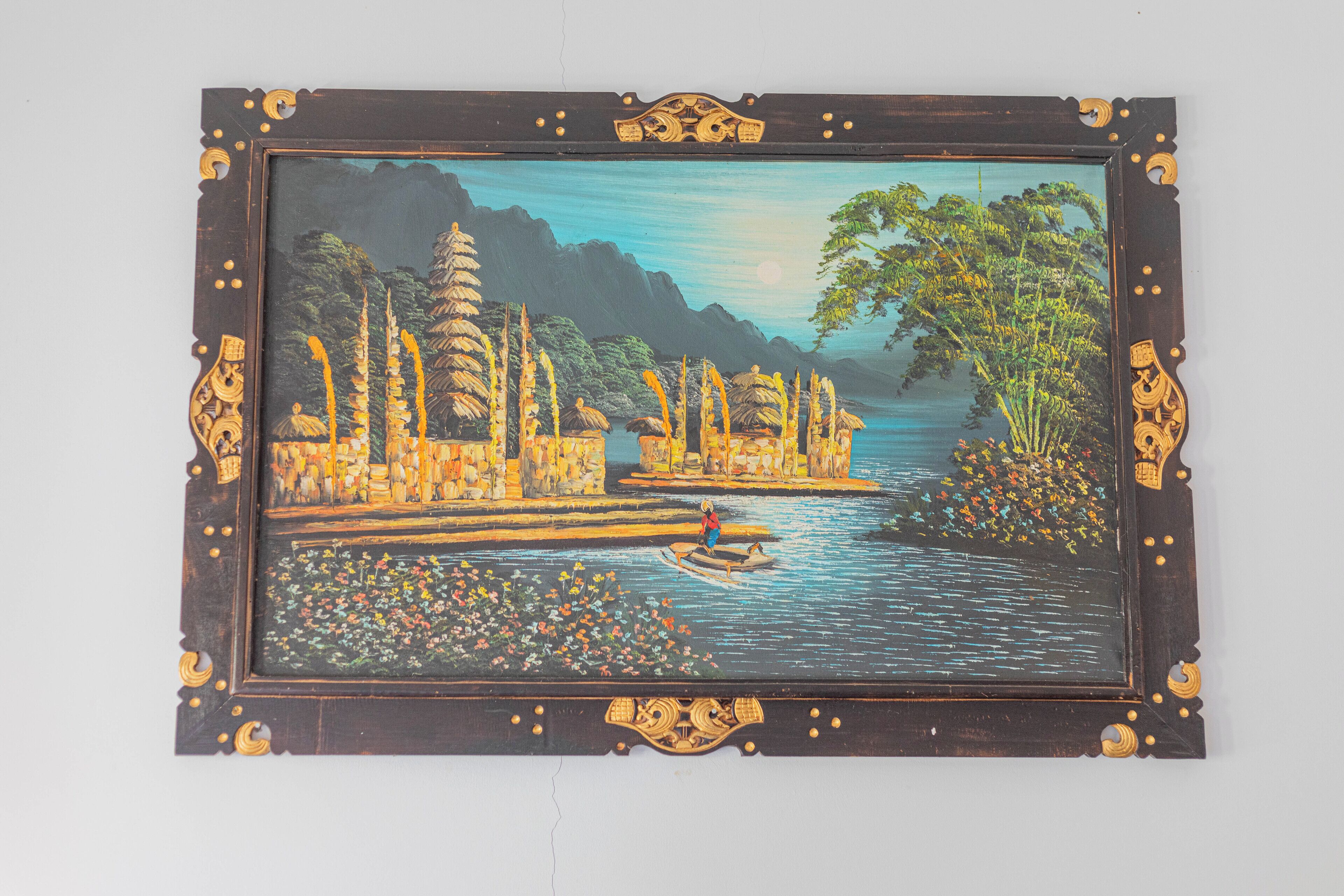 Un tableau encadré représentant une scène de rivière, avec des bâtiments traditionnels et un bateau.