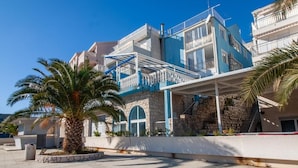A coastal hotel with a blue and white facade, a palm tree in the foreground, and a clear blue sky. - 1 Double room with Private Parking (Neum)