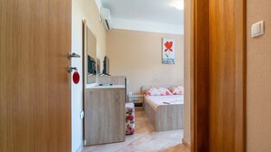A bedroom with a bed, a bedside table, a mirror, and a wall-mounted air conditioner.