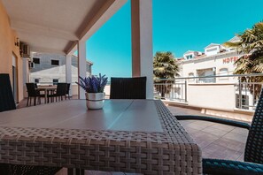 Un balcon avec une table et des chaises, un pot de fleurs et une vue sur un immeuble d’hôtel.
