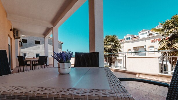 Ein Balkon mit Tisch und Stühlen, einem Blumentopf und Blick auf ein Hotelgebäude.