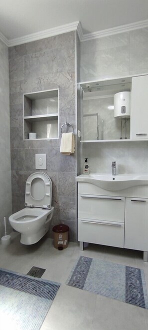 Une salle de bain moderne équipée de toilettes, d’un lavabo et d’une douche.