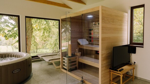 Un cuarto de sauna con recinto de vidrio, bancos de madera y un jacuzzi.