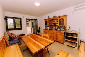 A spacious kitchen with a wooden dining table, chairs, and a built-in cabinet with glass doors. - Holiday Home with private garden and hot tub (Oroslavje)