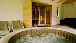 Una habitación con bañera de hidromasaje, armarios de madera y un sofá negro.