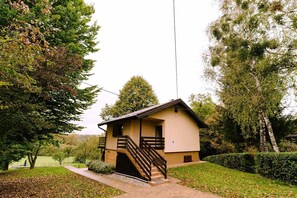 A small, single-story building with a wooden staircase leading to a balcony. - Holiday Home with private garden and hot tub (Oroslavje)