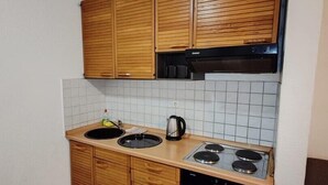 Una cocina compacta con armarios de madera, estufa a gas y horno integrado.