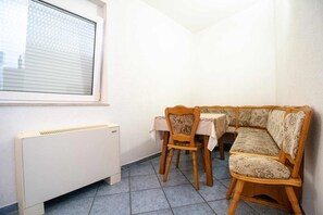 A corner room with a radiator, a window, a wooden chair, a table, and a sofa.