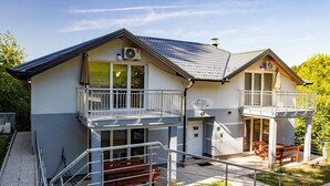 Ein zweistöckiges Gebäude mit Balkonen, Außenbestuhlung und einer Klimaanlage.