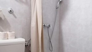 Une salle de bain avec des toilettes, une douche et un rideau.