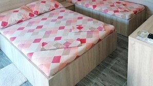 Une chambre avec deux lits, chacun agrémenté d’une couvre-lit à motifs, d’une tête de lit en bois et d’une petite table de chevet.