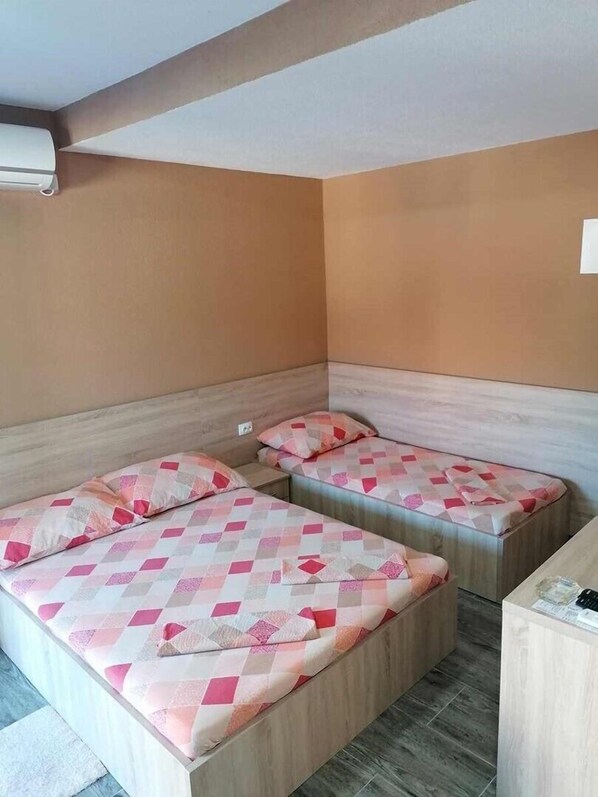 Una habitación con dos camas, cada una con una colcha estampada, un cabecero de madera y una mesita de noche pequeña.