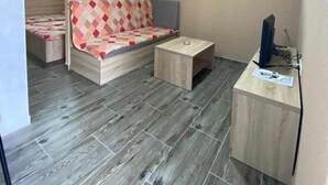 Una habitación compacta con sofá, una mesita y un escritorio con computadora.