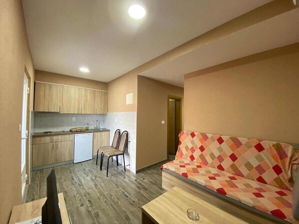 A compact living space with a kitchenette, a sofa, and a dining area.