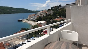 A balcony with a view of a lake, buildings, and a chair.