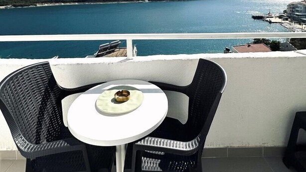 A balcony with a table and chairs overlooking a coastal view.