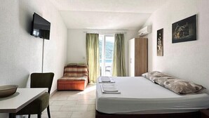 A hotel room with a bed, a desk, a chair, a television, and a window with curtains.