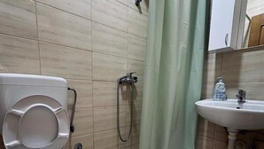 A bathroom with a toilet, shower, and sink.