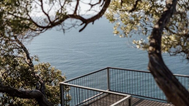 A view of a body of water with a wooden deck and metal railing.
