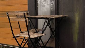 Une table et une chaise pliantes, adossées à un mur en bois près d’une fenêtre.