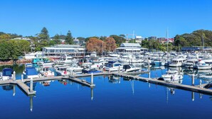 A marina with numerous boats docked, a clear blue sky, and buildings in the background.