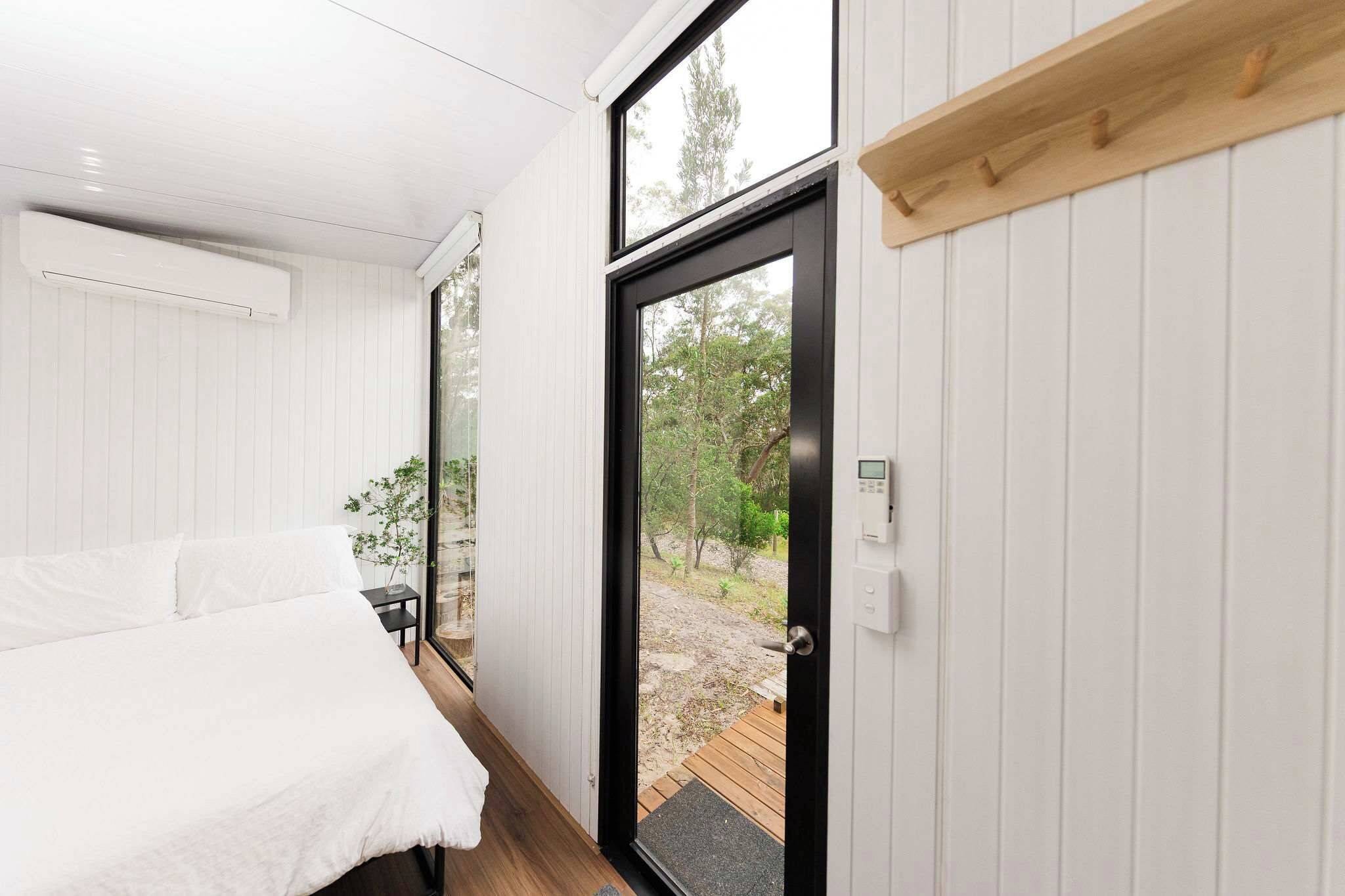 Un dormitorio con cama, una mesita y una puerta que da a un espacio exterior.