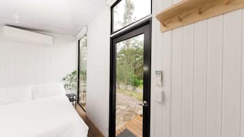 Un dormitorio con cama, una mesita y una puerta que da a un espacio exterior.