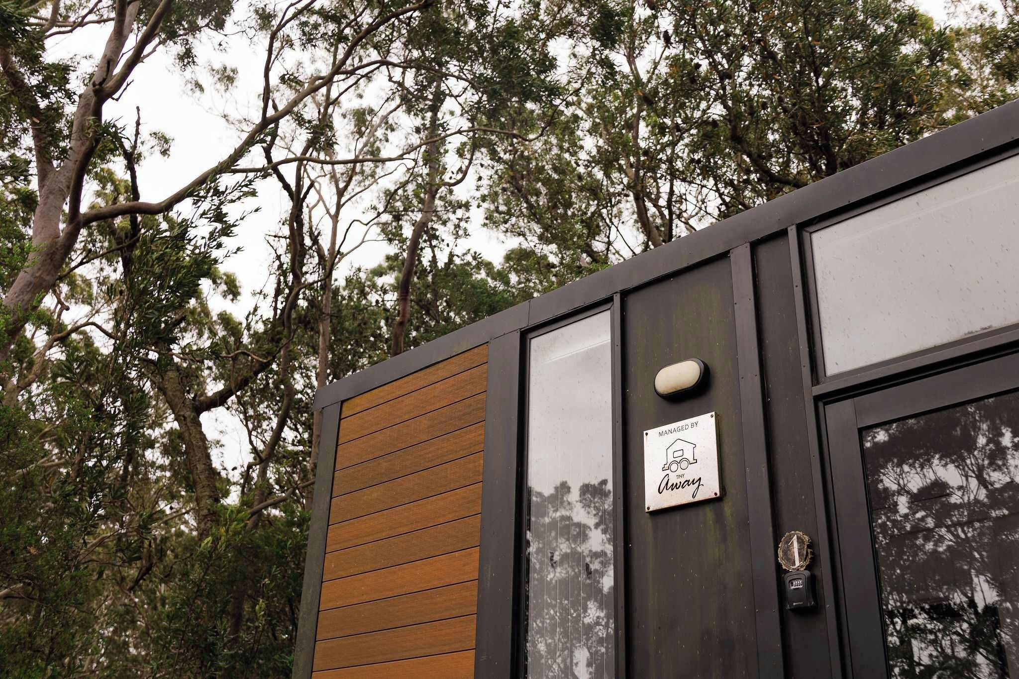 Il s’agit d’un bâtiment moderne doté d’une façade en panneaux de bois et d’une porte en verre. Une enseigne indique qu’il est géré par Tiny Away.