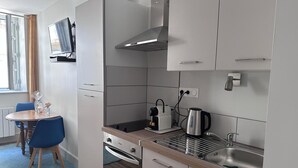 Ett kompakt kök med en inbyggd ugn, en vattenkokare och ett handfat.