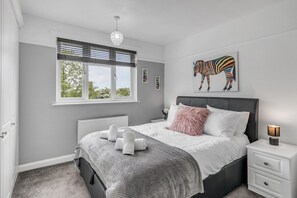 A bedroom with a bed, bedside table, and a window with blinds.